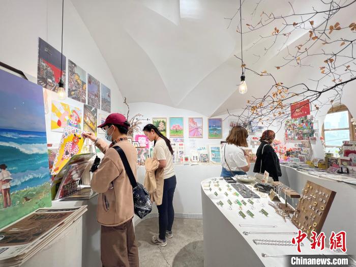 圖為藝術(shù)品商店內(nèi)，顧客挑選插畫作品?！＄婌?攝