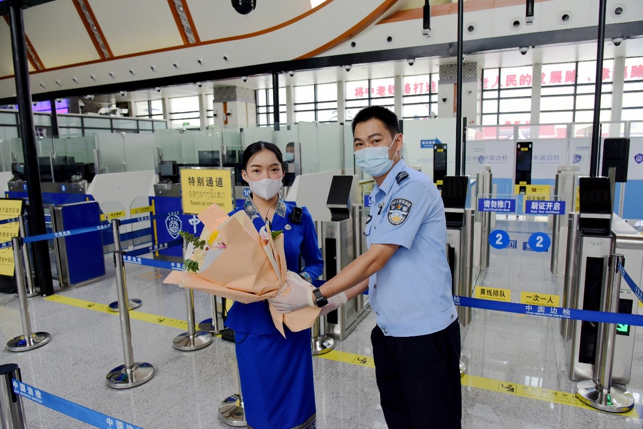 磨憨出入境邊防檢查站民警為中老鐵路第100萬名出入境旅客，D888次國際旅客列車老撾籍乘務(wù)員森達拉·妮緹婭（Sengdala Nitiya），送上鮮花。黃遠飛 攝