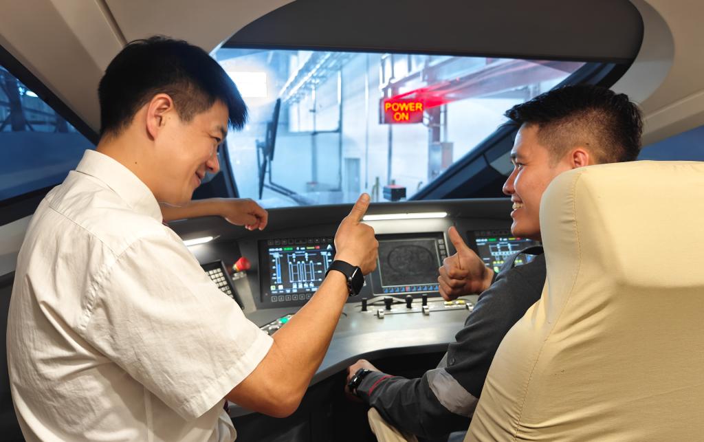 8月25日，在印度尼西亞萬隆的雅萬高鐵德卡魯爾動車所內(nèi)，中國師傅穆振（左）在向印尼火車司機(jī)塞蒂亞萬講解動車組出庫前的上電作業(yè)。