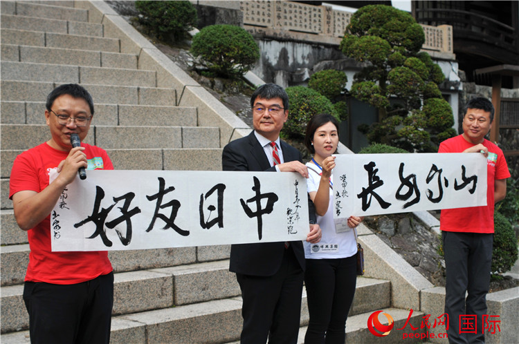 東京中國文化中心主任羅玉泉展示其為本次活動書寫的題詞“中日友好，山高水長”。人民網 蔣曉辰攝