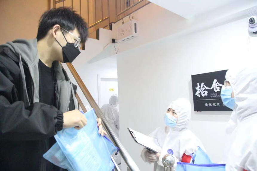 社區工作人員和志愿者身穿防護服上門送馬應龍大健康防疫包。徐帥攝