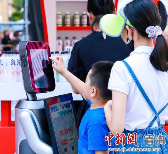 圖為一名小朋友正在和機器人“志愿者”進行互動。 沐聞 攝