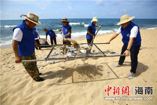 環保志愿者用篩網“淘”出海灘上的垃圾。