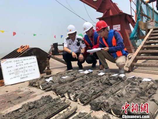 圖為勘察設計人員與海事局工作人員查看巖芯情況。　魏震 攝