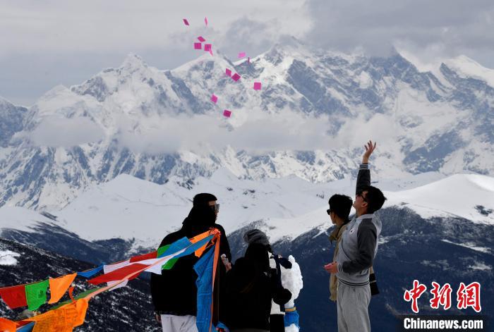 圖為5月14日，游客在西藏林芝色季拉山觀景臺拋灑“隆達(dá)”(風(fēng)馬旗，藏族民眾的一種祈福方式)。　李林 攝