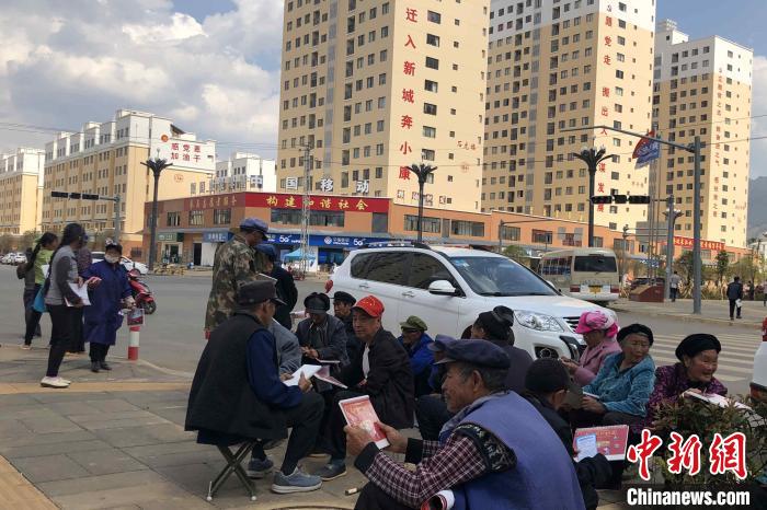圖為會澤縣城易地扶貧搬遷安置點內(nèi)，老人們聚在廣場上聊天，身后是他們的新家。　繆超 攝
