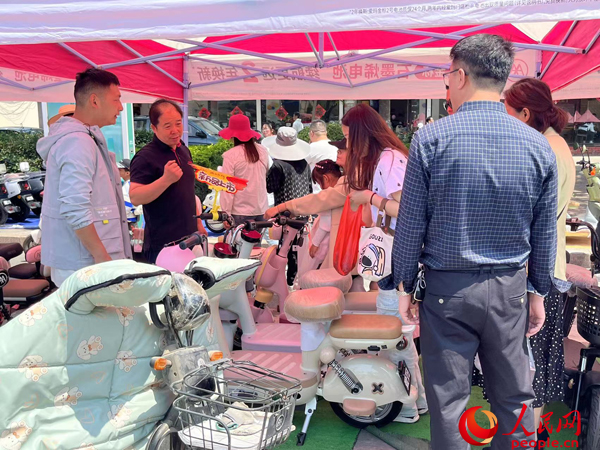 某電動自行車品牌工作人員向消費者介紹以舊換新相關(guān)情況。人民網(wǎng)記者 杜燕飛攝