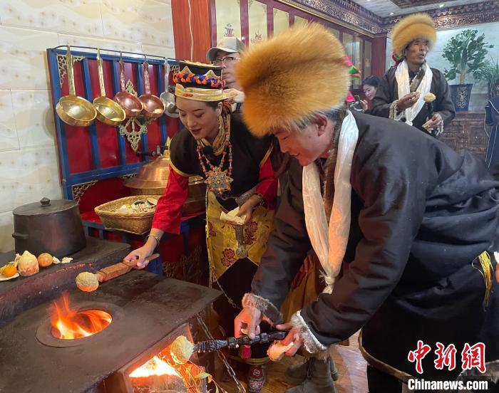 圖為人們在火上烤節(jié)日美食“結(jié)達(dá)”?！∪轿木?攝