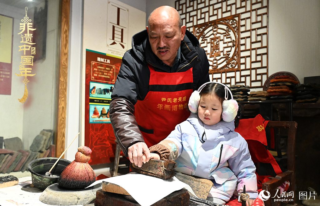 2025年1月27日，河南開封朱仙鎮木版年畫藝人尹國法指導小朋友研習年畫印制技藝。朱仙鎮木版年畫源自漢唐壁畫藝術，是中國木版年畫的鼻祖。2006年5月20日，朱仙鎮木版年畫經國務院批準列入第一批國家級非物質文化遺產名錄。人民網記者 王玉興攝